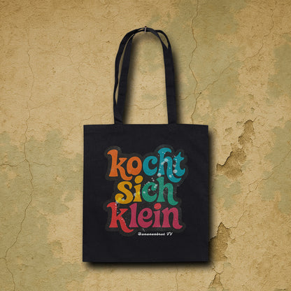 Nachhaltige Baumwolltasche in Schwarz mit Frontprint „kocht sich klein“ von Natura Umbra – hängendes Mockup zur Produktdarstellung.