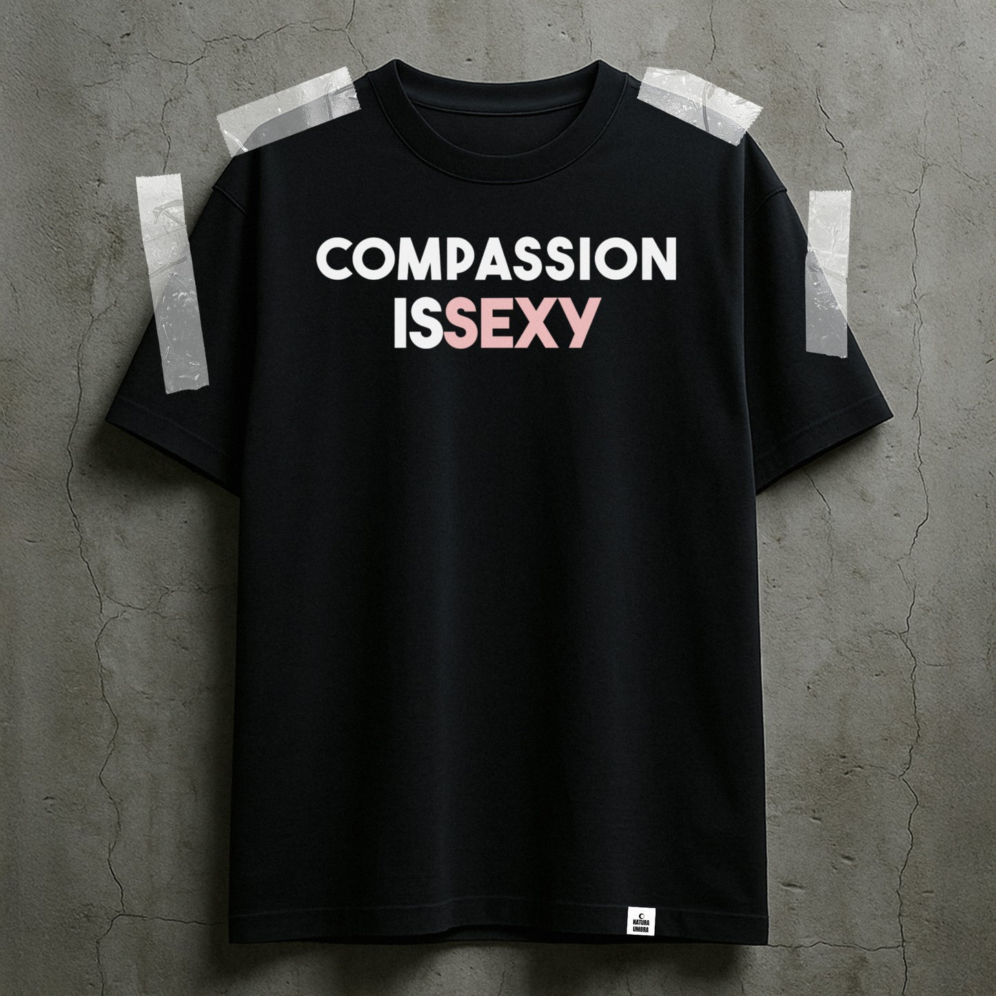 Nachhaltiges Unisex T-Shirt von Natura Umbra in Schwarz mit Frontprint „Compassion is sexy“ – Stanley/Stella Creator 2.0, dargestellt als taped Flatlay.