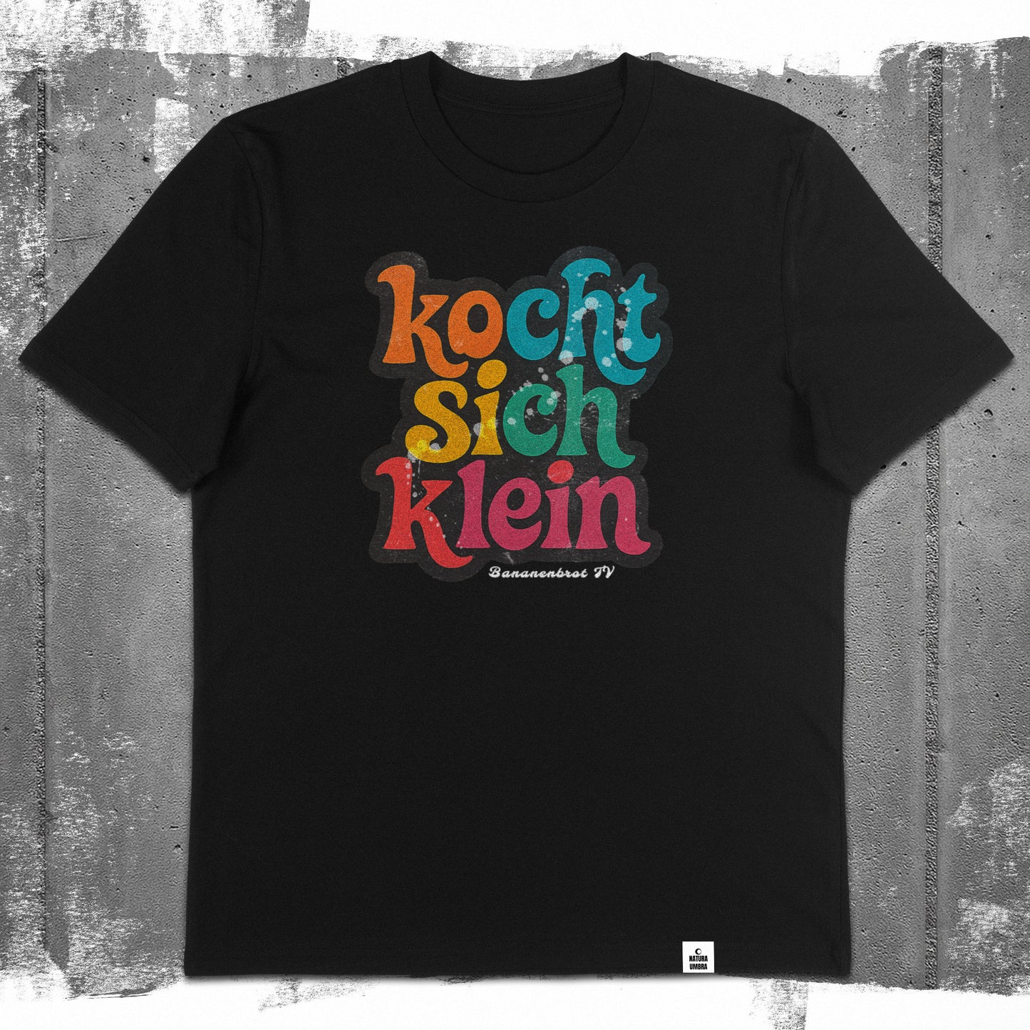 Nachhaltiges Unisex T-Shirt von Natura Umbra in Schwarz mit dem Frontprint „Kocht sich klein“ – Flatlay des Stanley/Stella Creator 2.0.